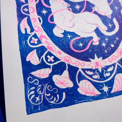 Blue and pink risograph print of a symmetrical, folk-like cat design with foliage surrounding, super close up on foliage